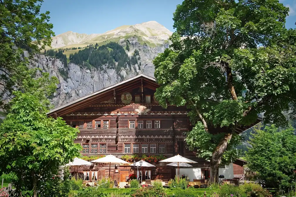 Das Haus zwischen zwei Bäumen, dahinter die Berge