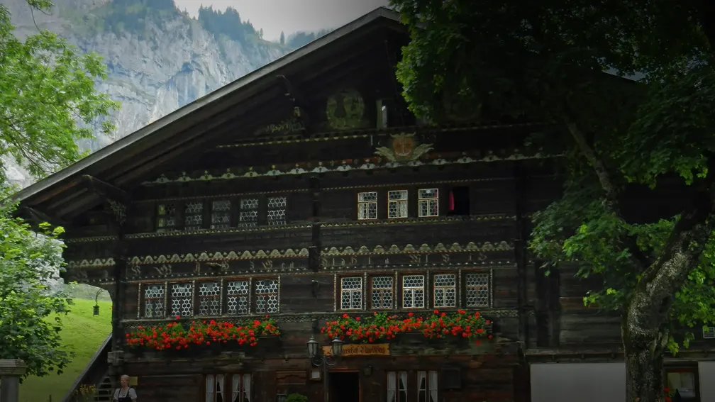 Die ganze Fassade mit Fensterreihen, Geranien und Garten