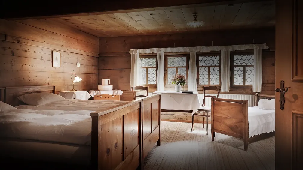 Zimmer mit Holzbetten und Fensterreihe
