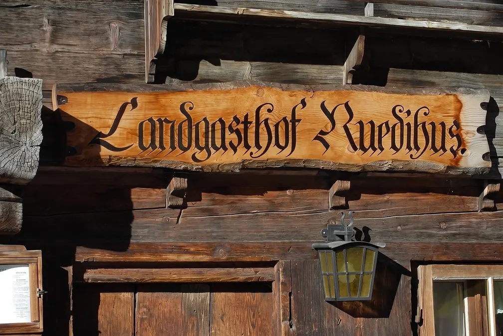 Holzschild «Landgasthof Ruedihus» in Fraktur über der Tür