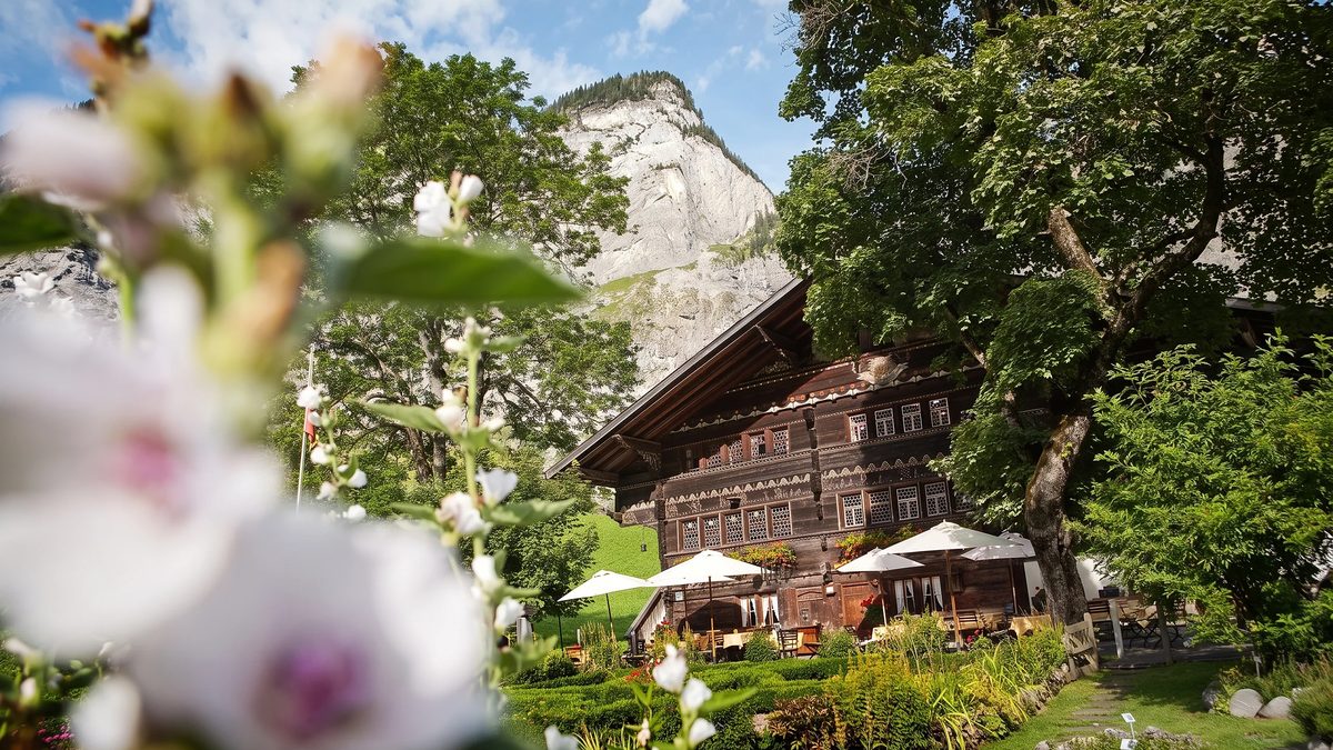 Das Ruedihus hinter Blüten, davor der Garten